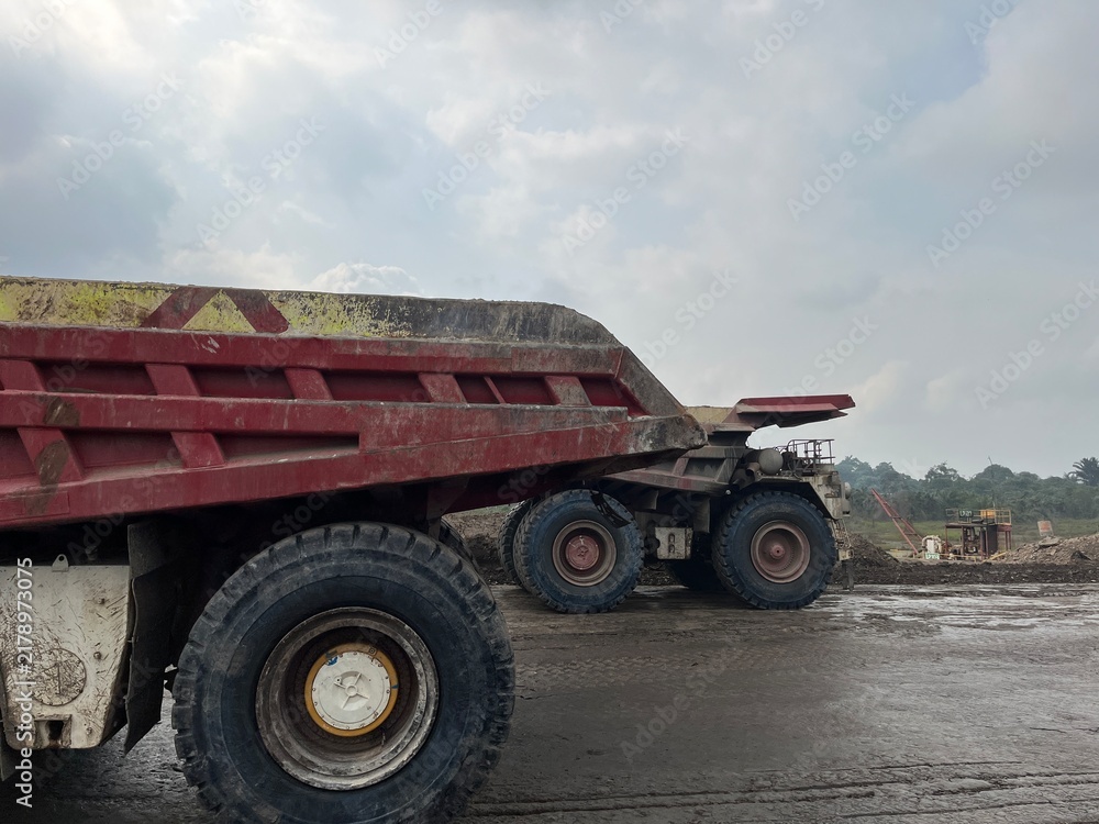 Fototapeta premium Close up profile view of massive mining dump truck wheels and body on haul road at mine site
