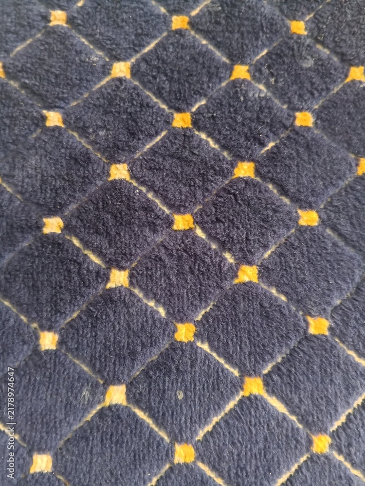 Obraz premium Quilted navy blue fabric texture with yellow diamond pattern for background design.