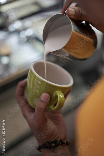 Fotografie Close-up view of steamed milk being poured into a vibrant yellow coffee cup, creating a smooth and creamy coffee beverage