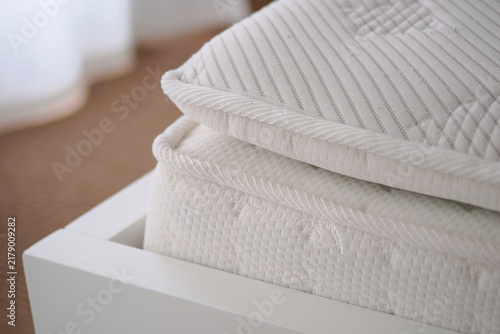 Soft mattress on a bed frame in a bright room