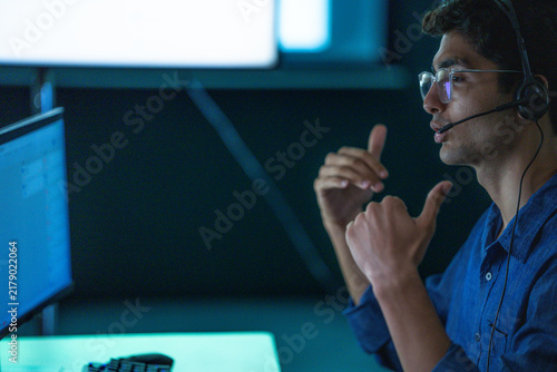 Cuadro en lienzo A male technical support agent wearing a headset at a bright service desk smiles