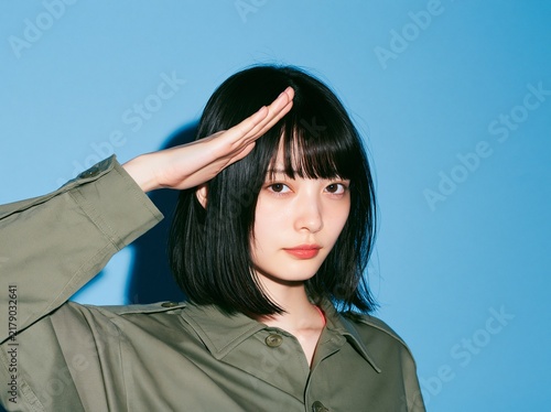 Fototapeta カーキ色のミリタリー風シャツを着用し敬礼をするお茶目な女性
