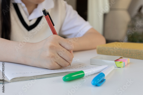 ノートに筆記する学生の手のクローズアップ