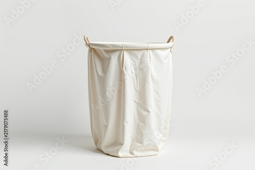 A minimalist, white fabric laundry basket with handles, standing empty against a plain white background.
