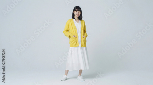 Fototapeta 黄色のカーディガンと白いワンピース姿で立つ笑顔の日本人女性