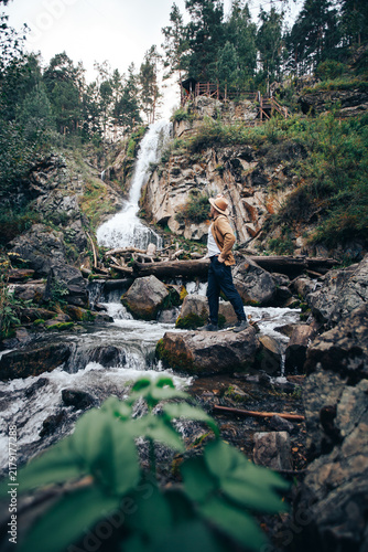 Картината върху платно Young caucasian male exploring waterfall in forested mountain landscape Altay Ru
