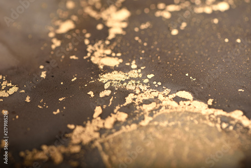 Artistic background with dark brown and gold swirls; photo of the surface.