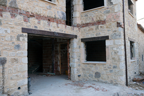 Stone house undergoing renovation with open windows