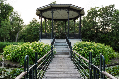 Fotografie Ornate black gazebo in a lush green park