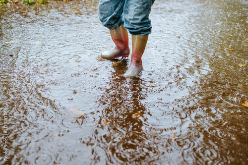 Obraz na plátně Child in rain boots standing in a rain puddle