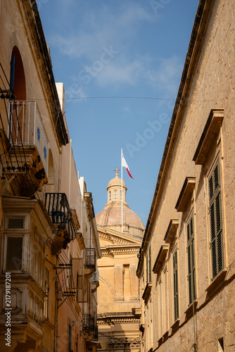 Foto View of church dome down narrow street in Malta