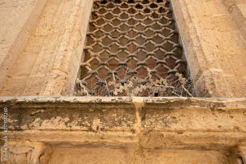 фотографія Ancient stone window with bird deterrent spikes