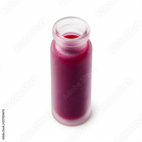A small frosted glass bottle filled with vibrant purple liquid isolated on a white background with cylindrical glass container fresh pressed elixir 