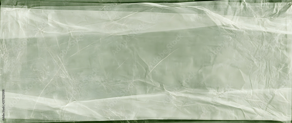 Obraz premium A textured old translucent tracing paper with folded layers, creases, and irregularities, displayed in a panoramic view with a greenish monochrome hue.