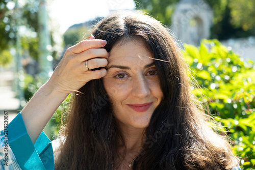 Obraz na płótnie Happy adult female with long dark hair smiling in natural outdoor light