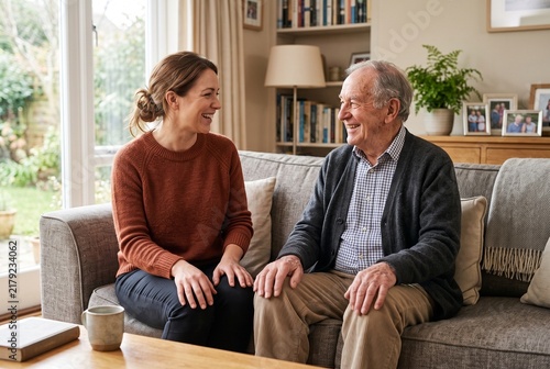 Adult Daughter Visiting and Laughing with Senior Father at Home on the Sofa