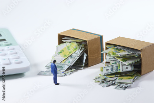 Financial management concept with money overflowing from cardboard boxes and miniature businessman
