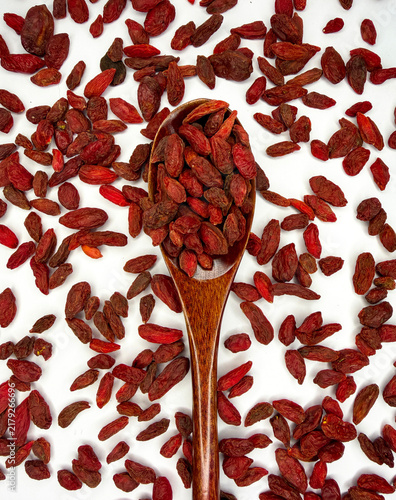 Obraz na plátně Dried Goji Berries Scattered Around Wooden Spoon on White Background, Healthy Su