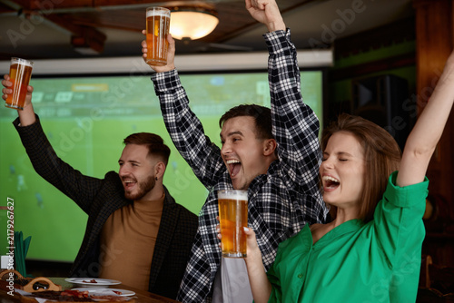 Foto Group of friends celebrating with beer cups enthusiastically with raised arms