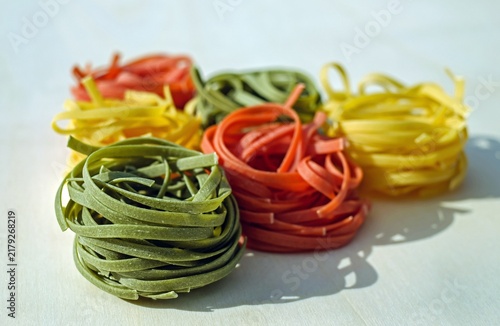 Foto Close-up of colorful tricolor tagliatelle fettuccine pasta nests made with spinach, tomato, and egg on a light background