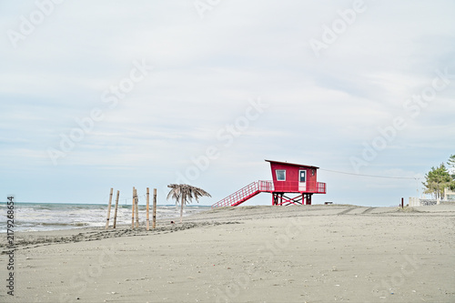 Red lifeguard tower on a quiet sandy Black Sea beach under an overcast sky, on the coast of Poti, Samegrelo-Zemo Svaneti region, Georgia.