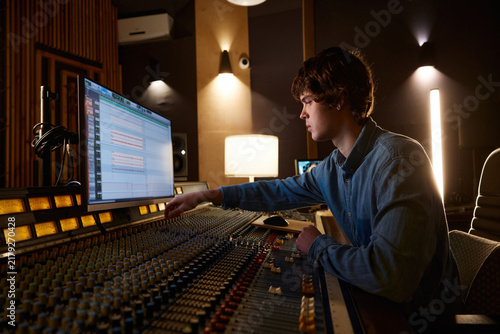 Принти на полотні Music producer focuses deeply amidst ambient studio setting with equipment