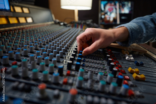 Bild auf Leinwand Detailed view of operators manipulating analog mixing knobs during session