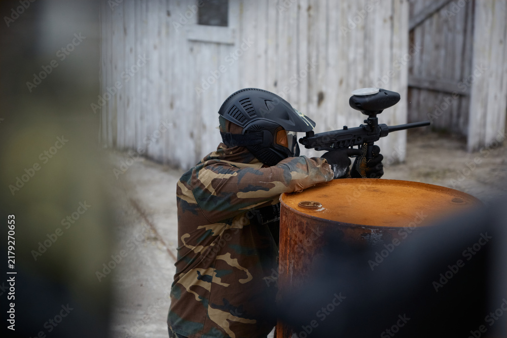 Obraz premium A soldier aims a gun while leaning on a drum, hiding behind