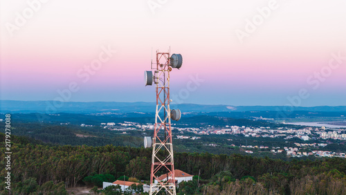 Telecommunications Tower Above Forest and Town at Twilight