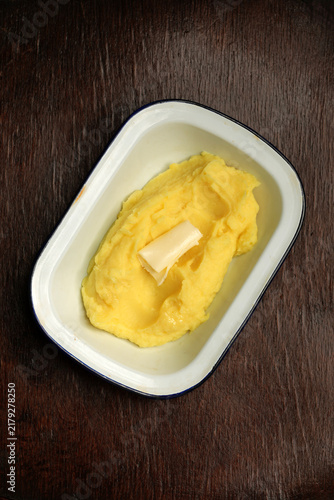 Foto Creamy mashed potatoes with butter roll in enamel dish close up
