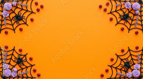 Halloween background featuring black spider webs and spiders in the corners on a bright orange backdrop