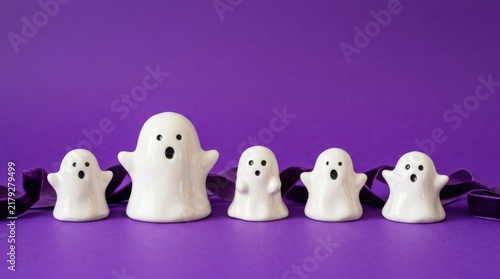 A row of cute white ghost figurines arranged on a vibrant purple background for Halloween decoration