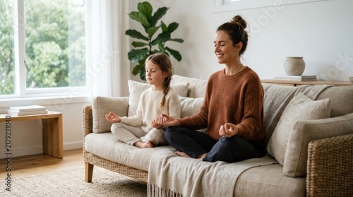 Mother and Daughter Meditating Together on Sofa at Home.