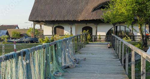 Sf. Gheorghe, Romania - April 25, 2025: Traditional fishery house and fishing nets drying on wooden pontoon, a rustic landscape in the Danube Delta