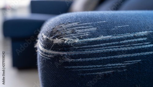 Close-up of a dark blue fabric couch showing multiple parallel cat scratch marks.