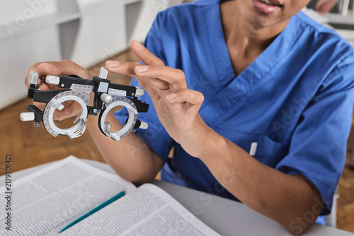 Fotografie Close-up of medical student hands holding an ophthalmic trial frame over an open textbook