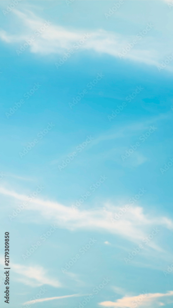 Obraz premium Vertical view of a soft blurred bright blue sky filled with wispy white clouds creating a calm peaceful and dreamy natural background