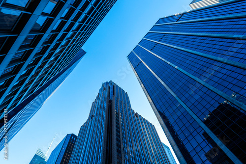 Modern skyscrapers and glass office buildings in business district, captured from low angle perspective with blue sky, symbolizing architecture, urban growth, corporate success, and city development.