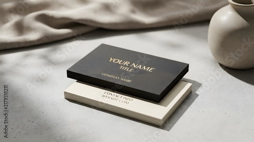 Black and white business card mockup on a textured stone surface with soft shadows.