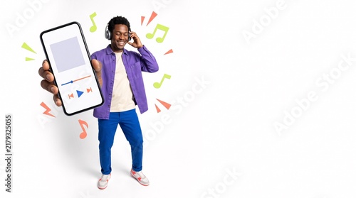 Young man showing smartphone with music player app on white background