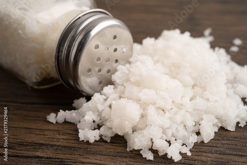 Fotografie Sodium chloride sea salt with salt shaker.