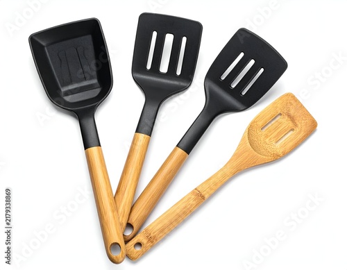 Close-up of four cooking utensils scoop, slotted spatula, and wooden spatula on white