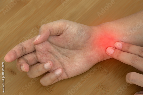 Wrist pain is shown by a person pressing the inner wrist, illustrating discomfort from hand strain repetitive use and possible tendon or nerve problems for medical care.