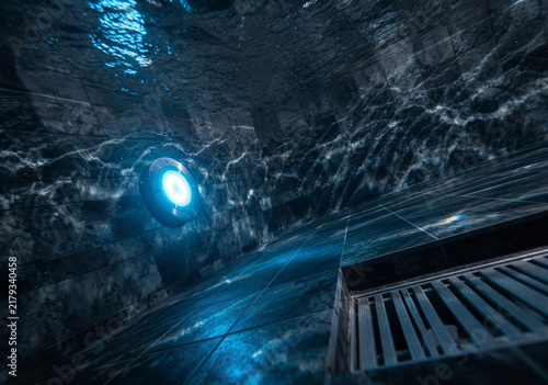 Underwater view of a luxury dark tiled swimming pool with a glowing blue LED light and a drain grille