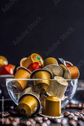 Assorted Coffee Capsules in Glass Bowl with Coffee Beans on Dark Background
