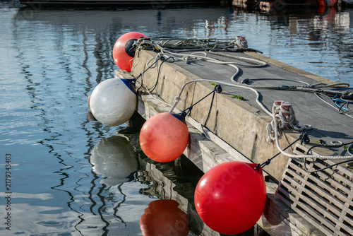 Wooden dock with mooring buoys reflected in calm harbor water