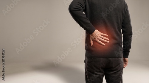 Man holding his lower back in pain, suffering from lumbar injury or muscle strain.
