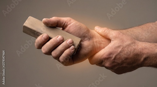 Person holding a wooden block while suffering from wrist pain and joint inflammation.