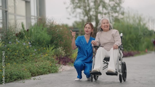 Caregiver walking with senior in wheelchair outdoors