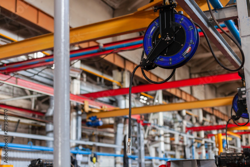 Foto Close-up of industrial retractable cable reel mounted on steel structure inside manufacturing facility